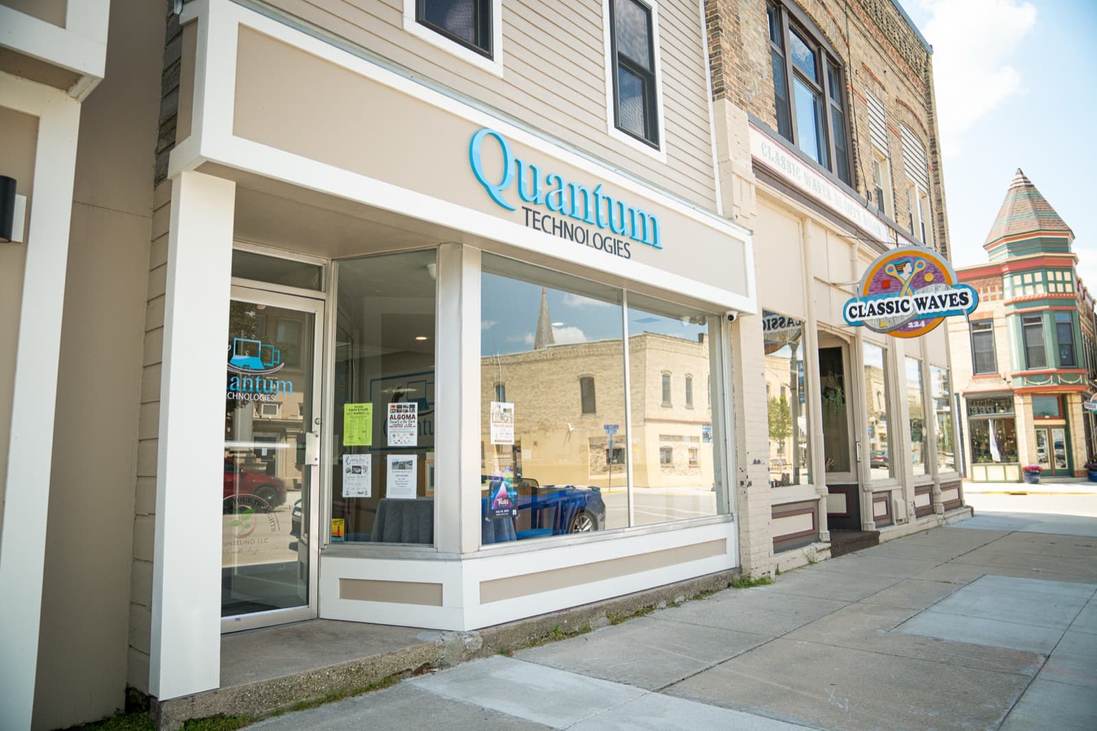 The Quantum Technologies storefront in Algoma, WI, with signage above the window on a downtown street.